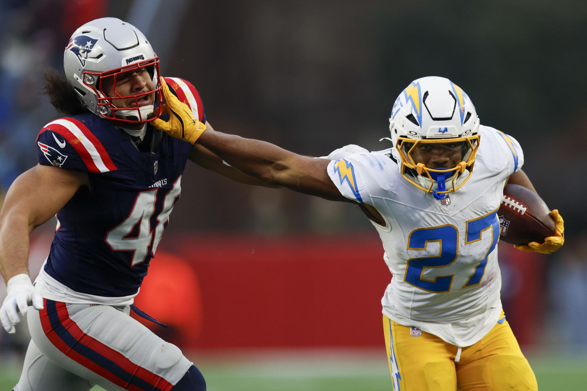 Chargers running back J.K. Dobbins (27) attempts to evade a tackle by Patriots linebacker Jahlani Tavai (48) in 2024.