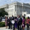 Members of the Congressional Black Caucus speak outside the U.S. Capitol in October. They are standing around a lectern that has microphones attached to it.