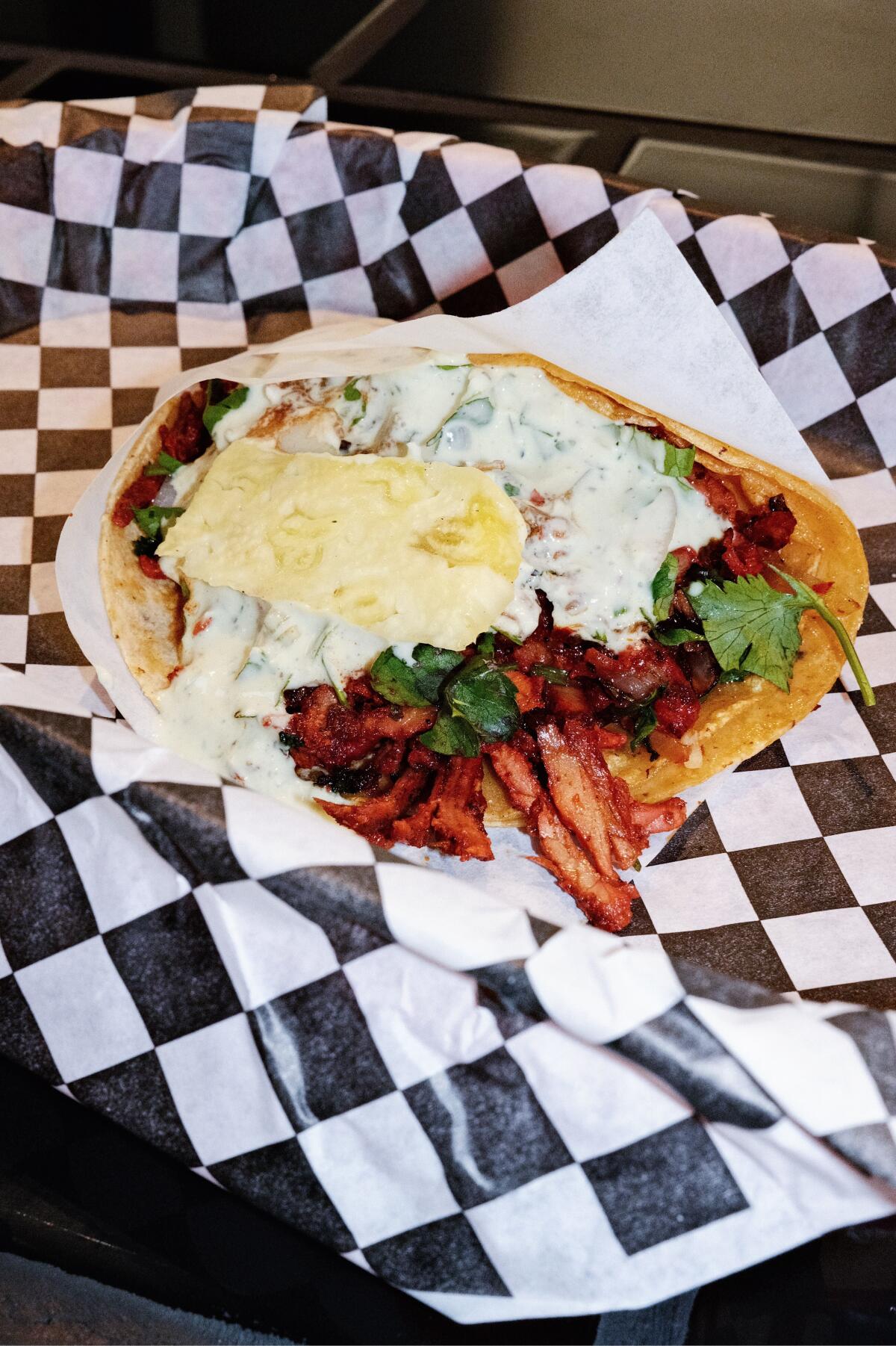 An al pastor taco on black-and-white checkered paper at Taqueria Frontera in Silver Lake.