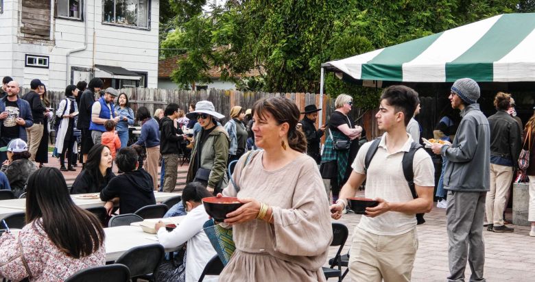 People carry bowls of food to tables in a courtyard at the Berkeley Thai Temple.