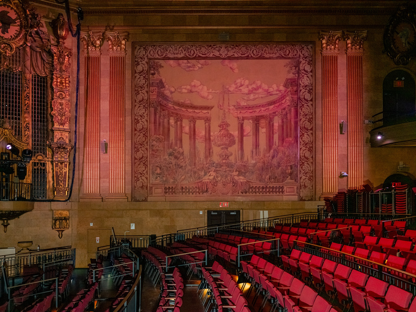 An ornate, circular ceiling with floral and geometric patterns surrounds a central, white, star-shaped chandelier, above intricately carved walls.