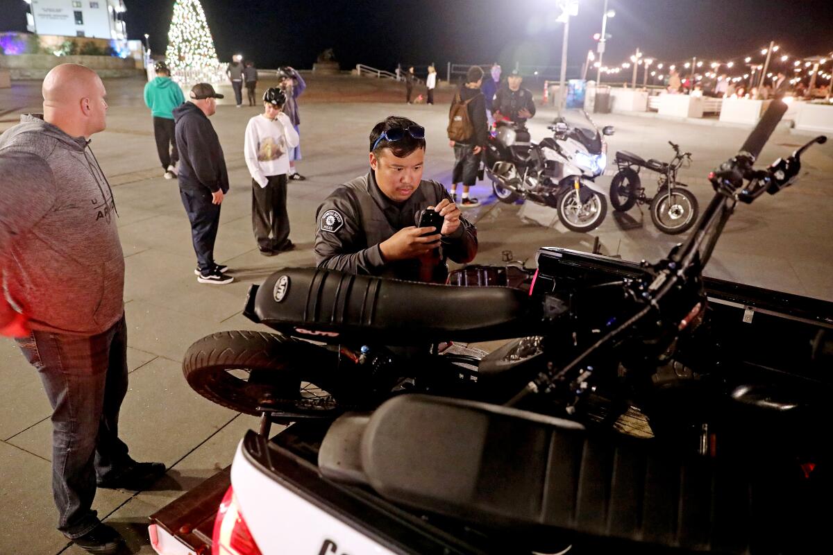 Two men check e-bikes at night.