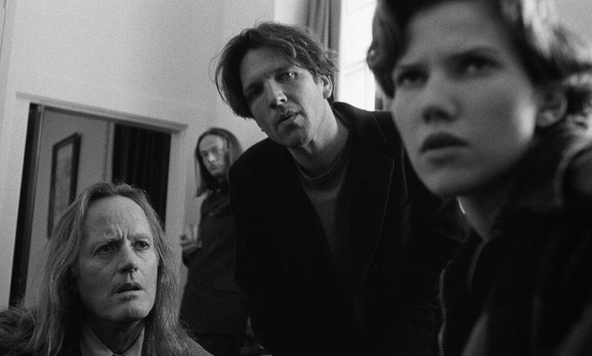 Four people peer into the lens.