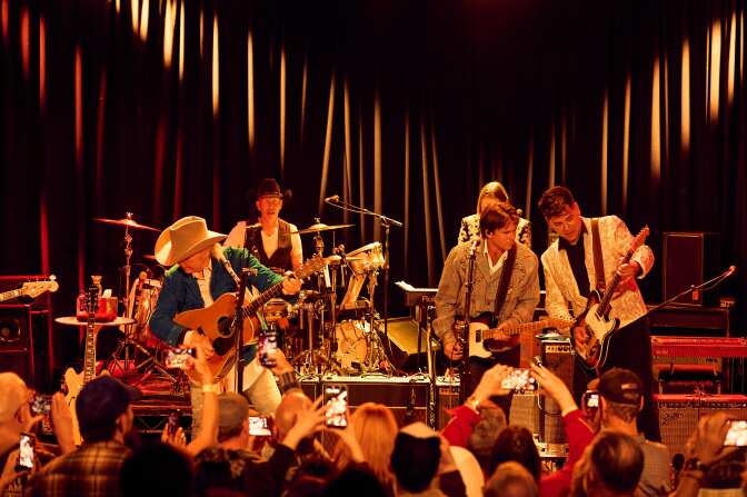Dwight Yoakam and Lukas Nelson take the stage at The Roxy. Yoakam wears a blue jacket and white cowboy hat.