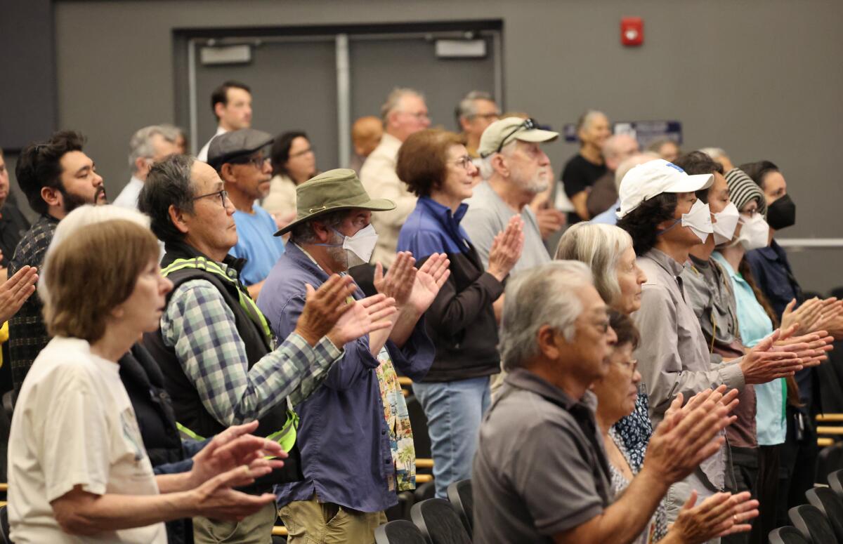 Audience members participate in a "peace clap" as they listen to speakers against the use of hydrofluoric acid 