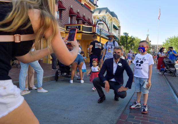 Cynthia Randez takes a picture of her son, Apollo Leisz, 7, with Chairman, Disney Parks, Experiences and Products, Josh D'Amaro on Main Street U.S.A. just after the gates opened in Anaheim, CA, on Friday, April 30, 2021. The resort's parks have been closed for 412 days due to the COVID-19 outbreak. (Photo by Jeff Gritchen, Orange County Register/SCNG)