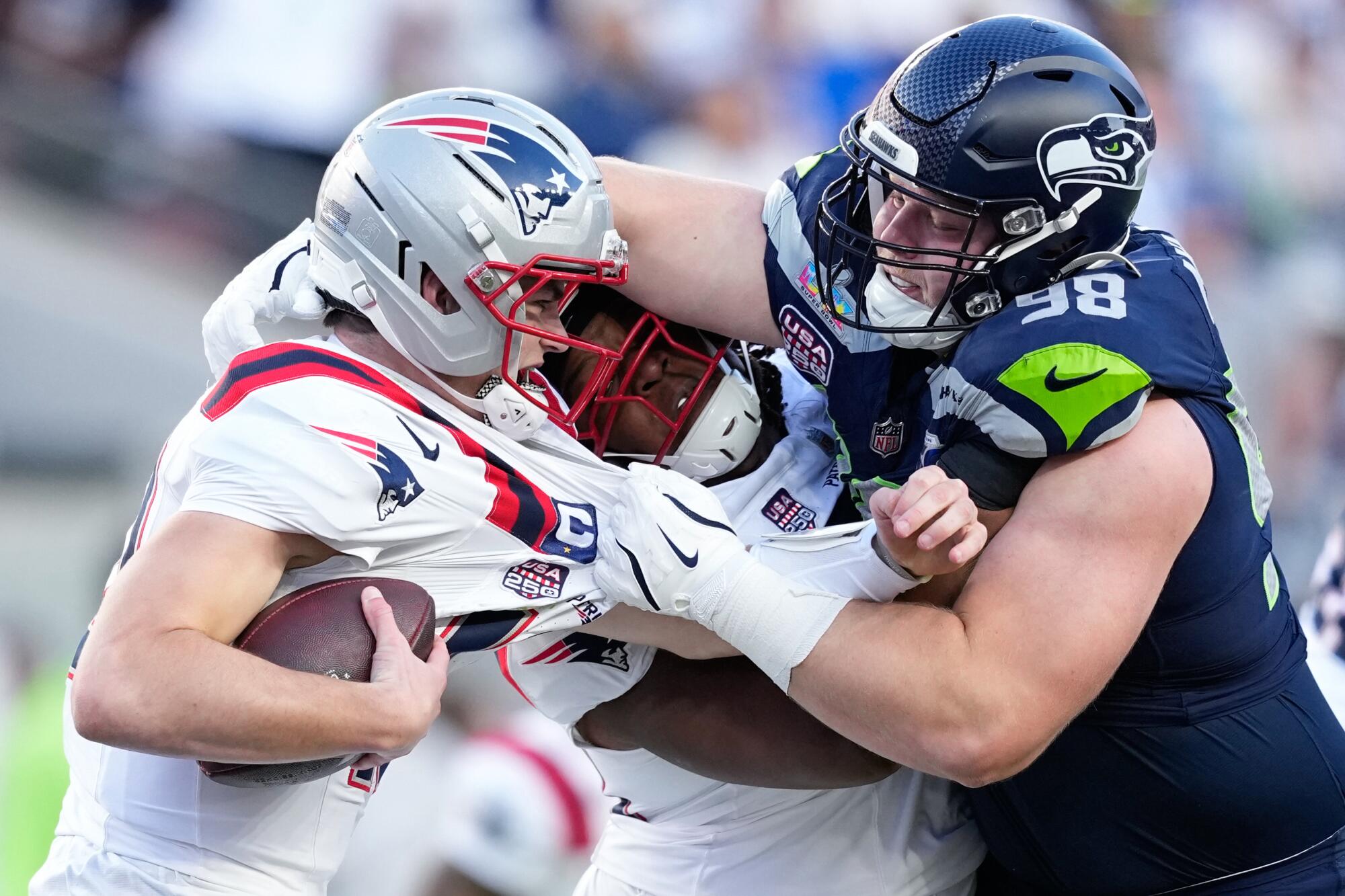 Seattle Seahawks defensive end Rylie Mills, right, sacks New England Patriots quarterback Drake Maye 