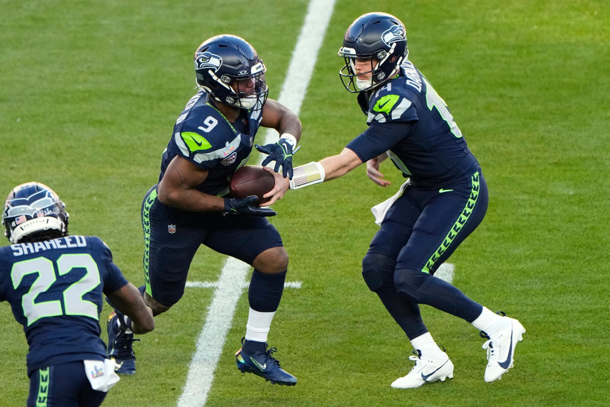 Seattle Seahawks quarterback Sam Darnold, right, hands off to running back Kenneth Walker III.