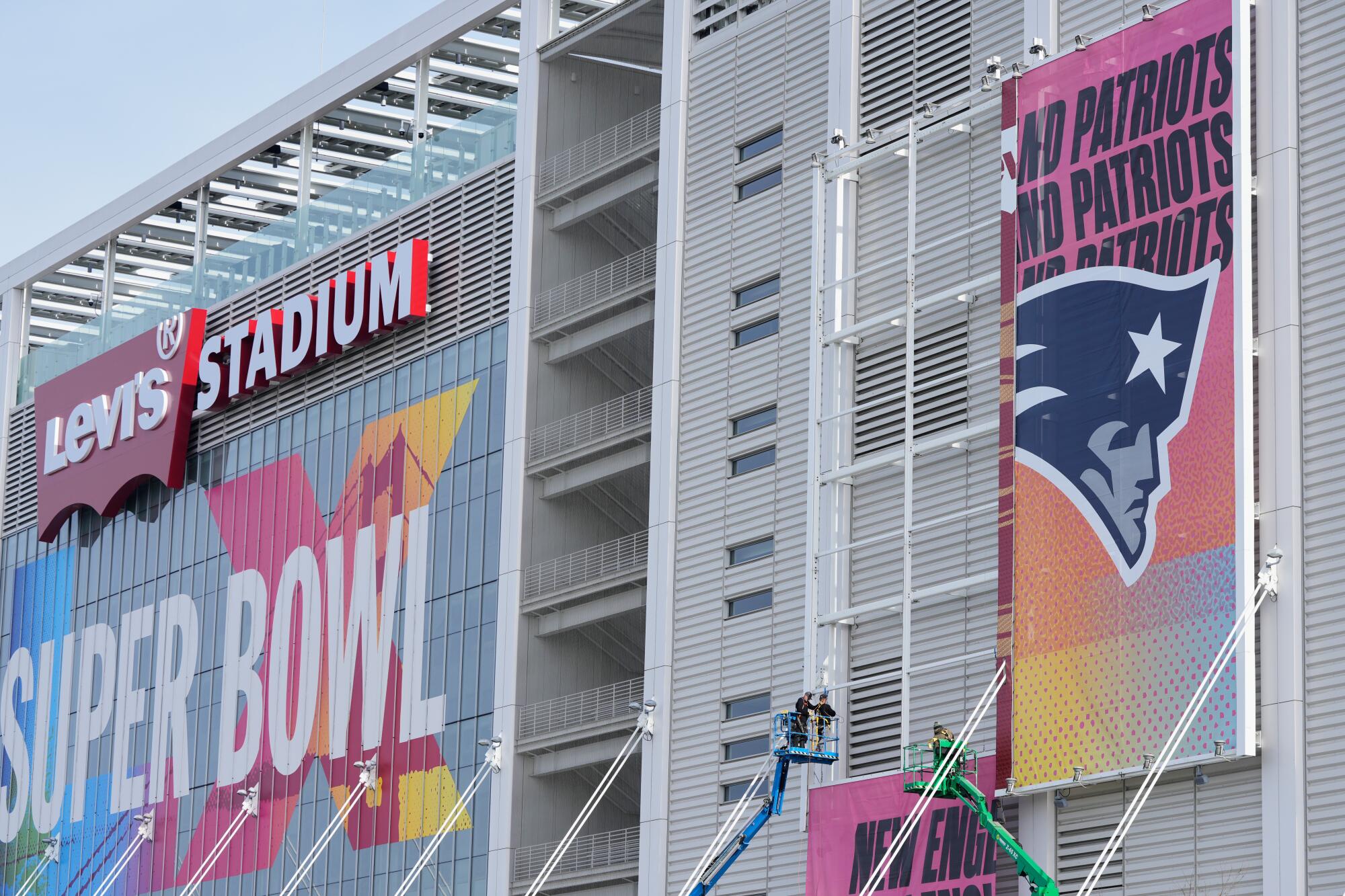 Workers add signs to Levi's Stadium ahead of Super Bowl LX between the Seahawks and Patriots in Santa Clara on Saturday.