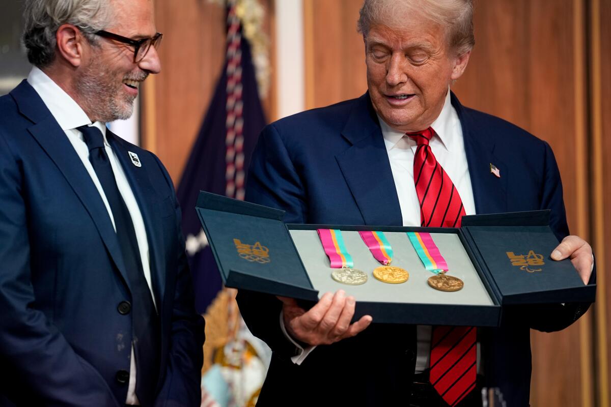 Casey Wasserman, chair of 2028 LA Olympics organizing committee, and President Trump look at Olympic medals.