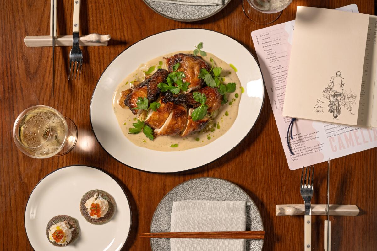 An overhead view of chicken and crab dishes on white plates with a menu to one side.