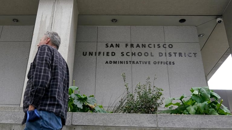 A pedestrian walks past a San Francisco Unified School District...