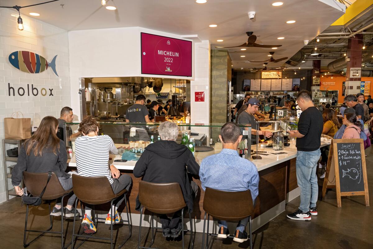 Diners seated at the counter during lunch rush at Holbox inside Mercado La Paloma  