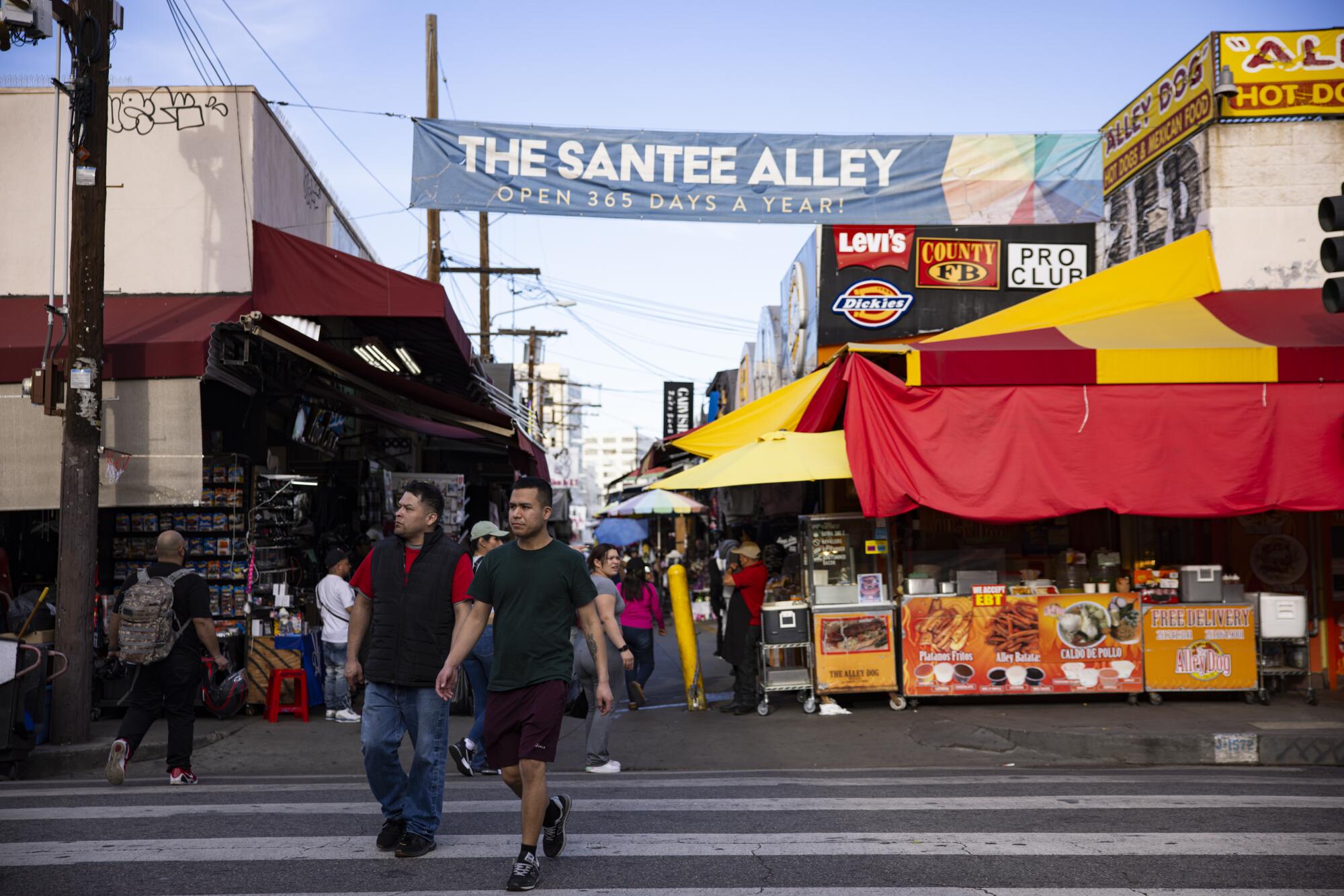 Visitors walk past shops in Santee Alleyin the Fashion District.