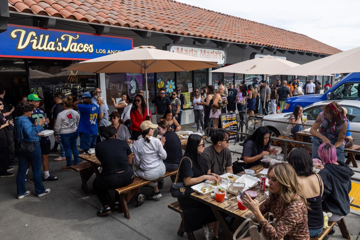 Patrons eat and line up outside of a restaurant