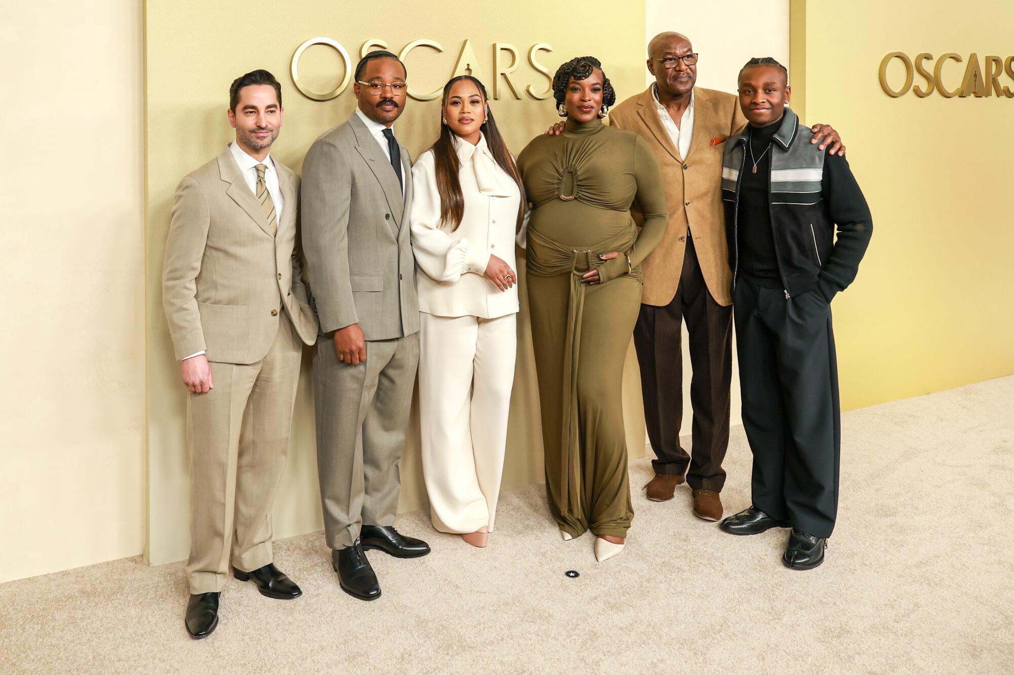 Sev Ohanian, Ryan Coogler, Zinzi Coogler, Wunmi Mosaku, Delroy Lindo and Miles Caton pose on the beige carpet. 