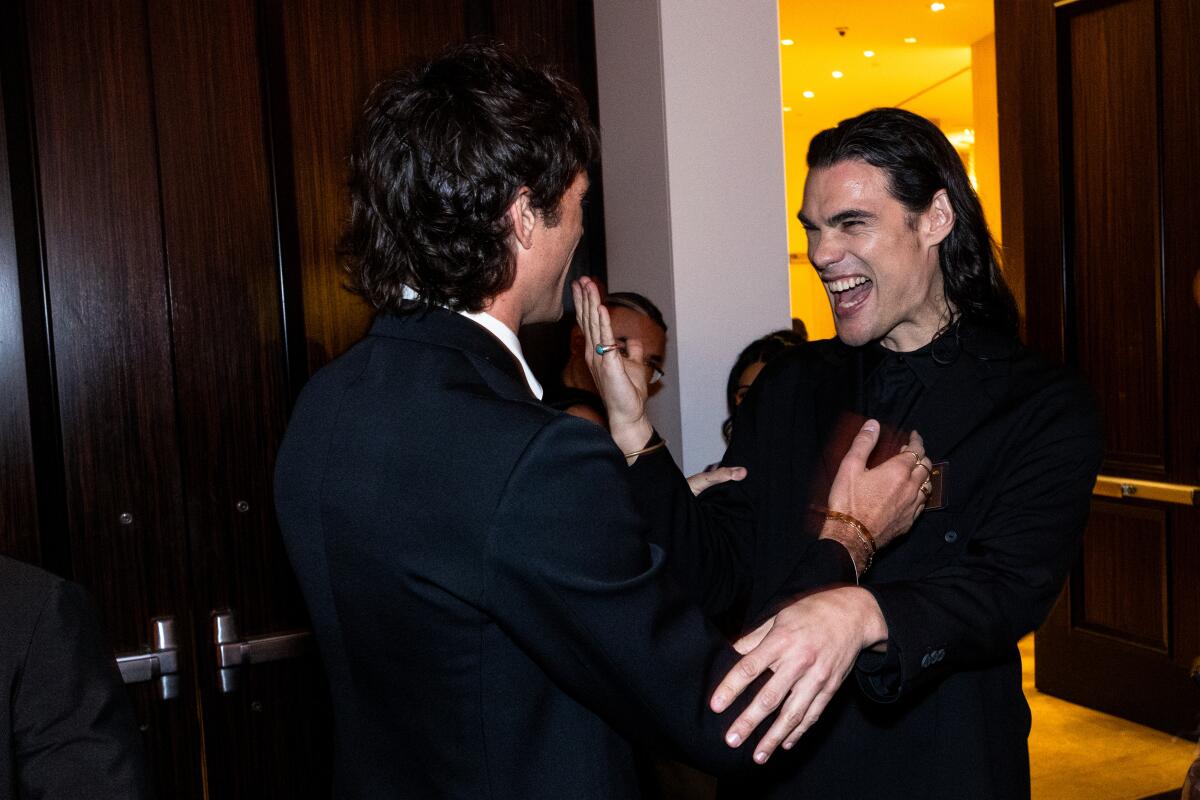 Two men smile and hug.