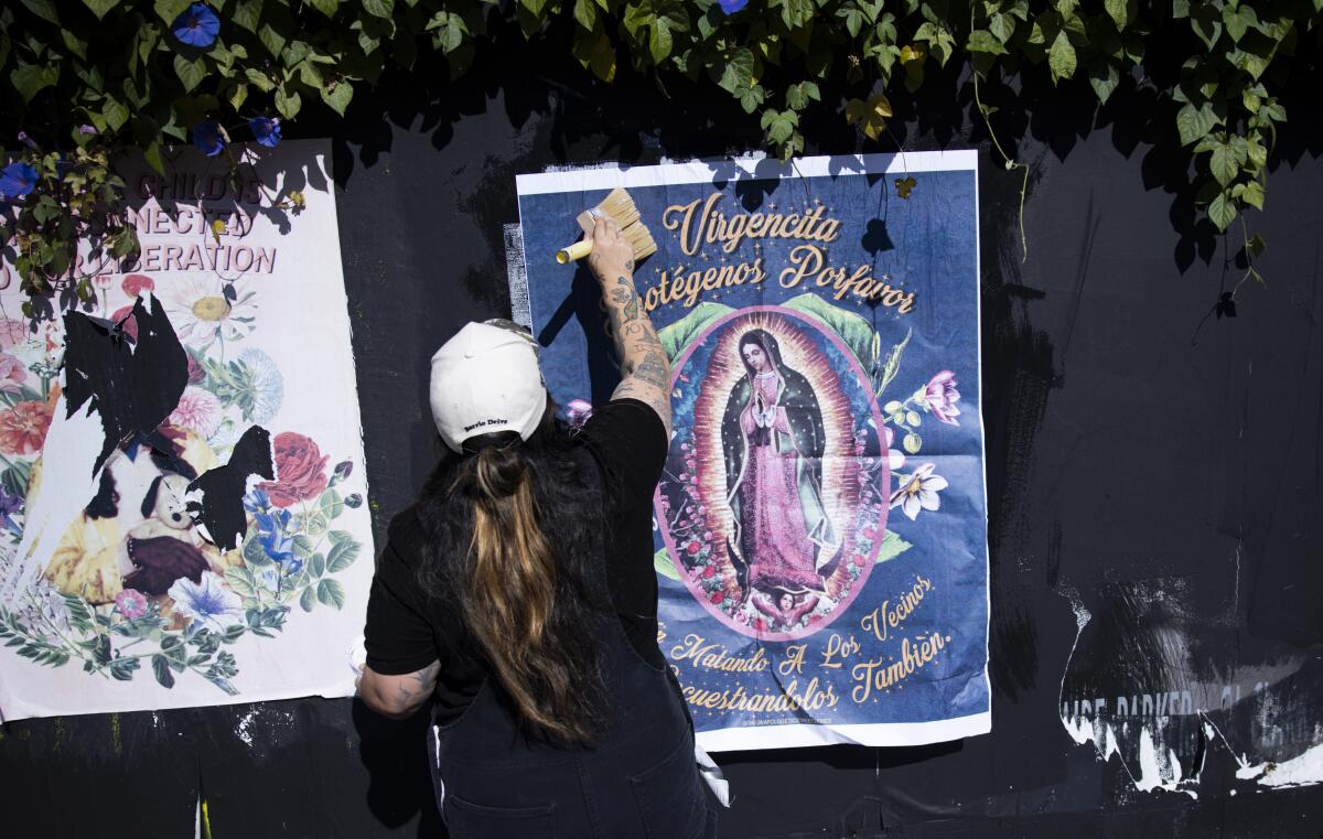 Johanna Toruño presses a poster of the Virgen de Guadalupe on a wall. 