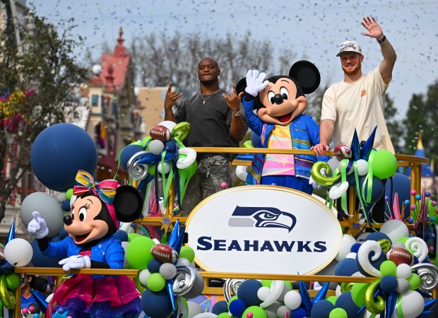 Seahawks quarterback Sam Darnold and running back Kenneth Walker III celebrate their Super Bowl victory over the Patriots during a parade down Main Street, U.S.A., at Disneyland in Anaheim on Monday. Seattle defeated the New England Patriots 29 to 13 in Santa Clara on Sunday. Jeff Gritchen Staff Photographer