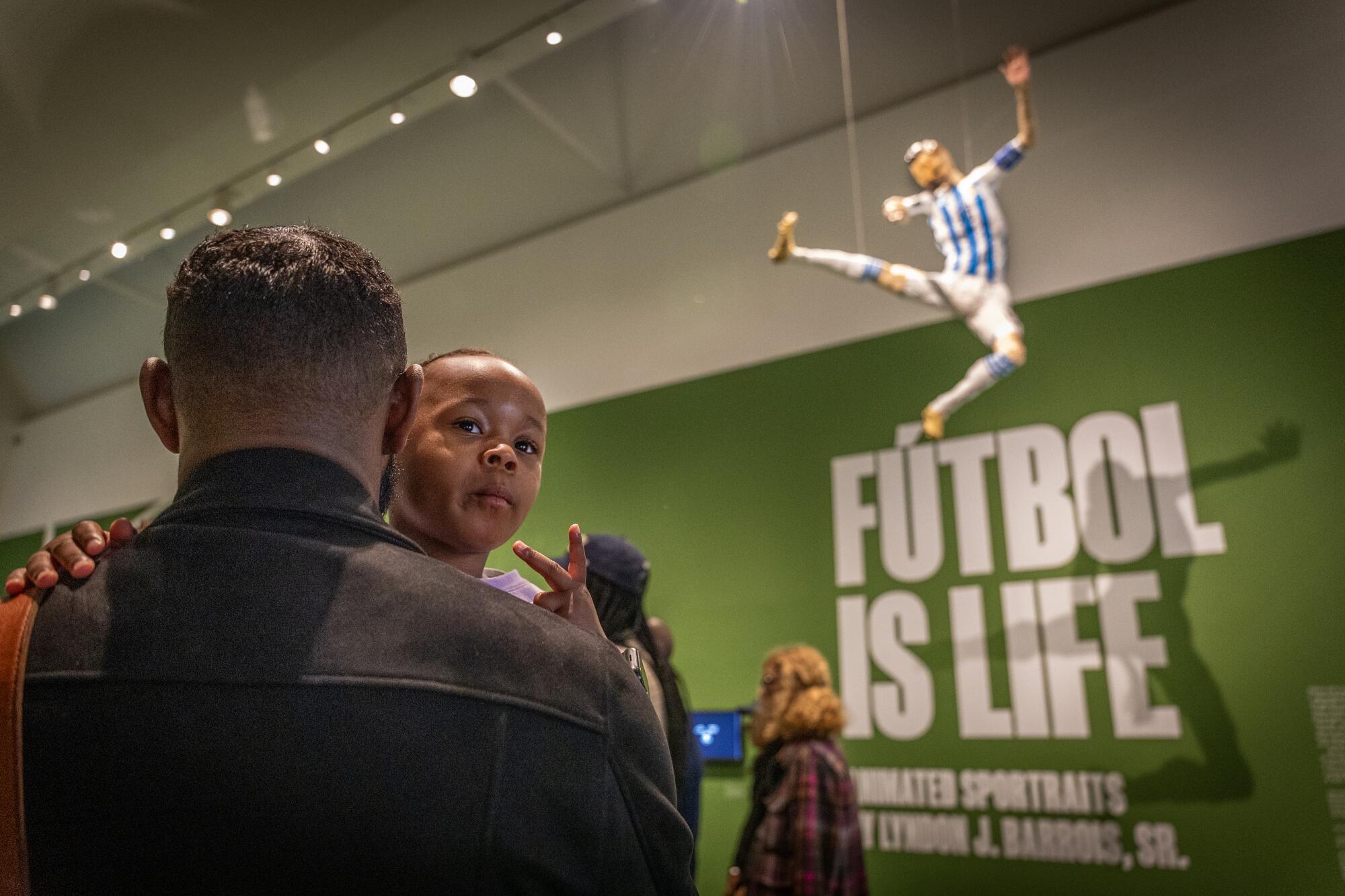 A father and daughter look on at an exhibition of miniature soccer figurines, including Lionel Messi.