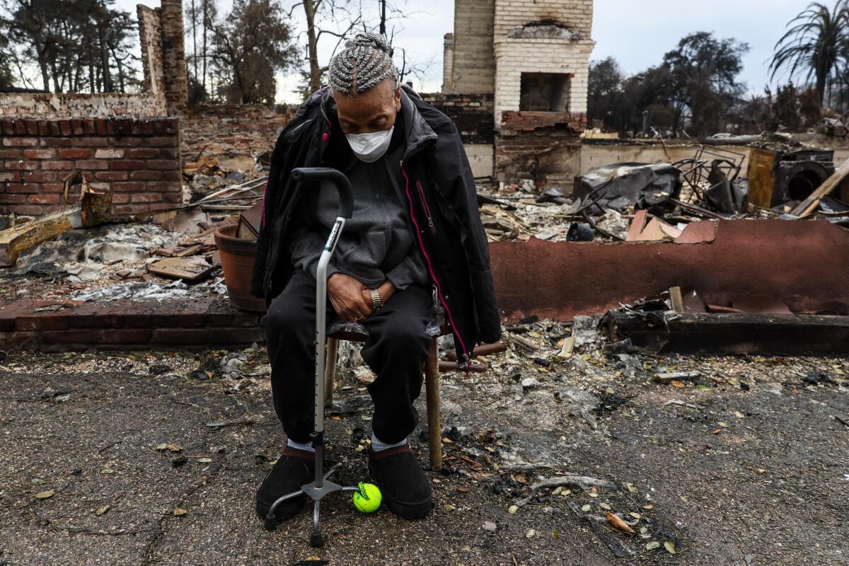 A woman sits outside the remains of a home burned down in a fire 