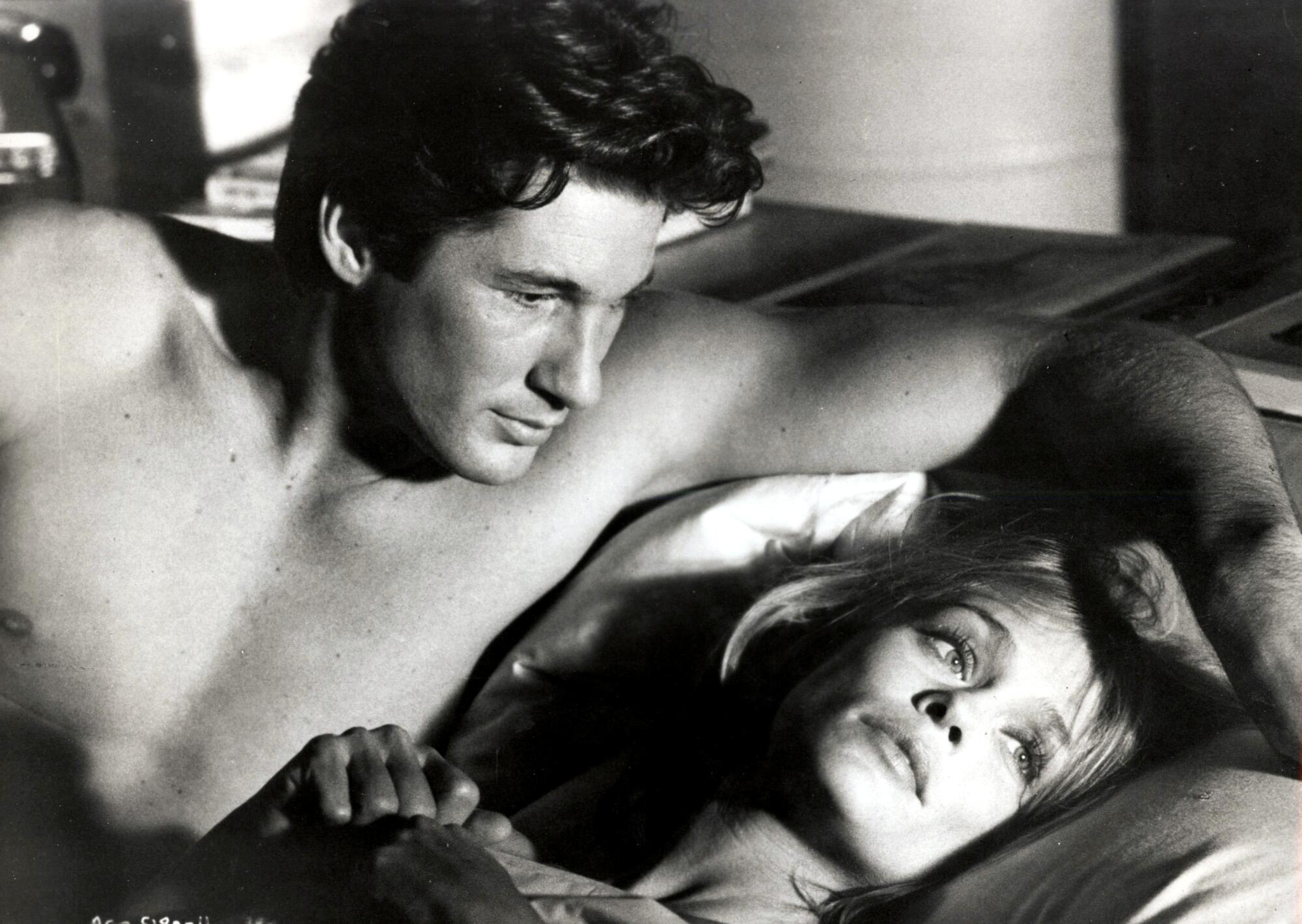 A man looks at a woman in bed.