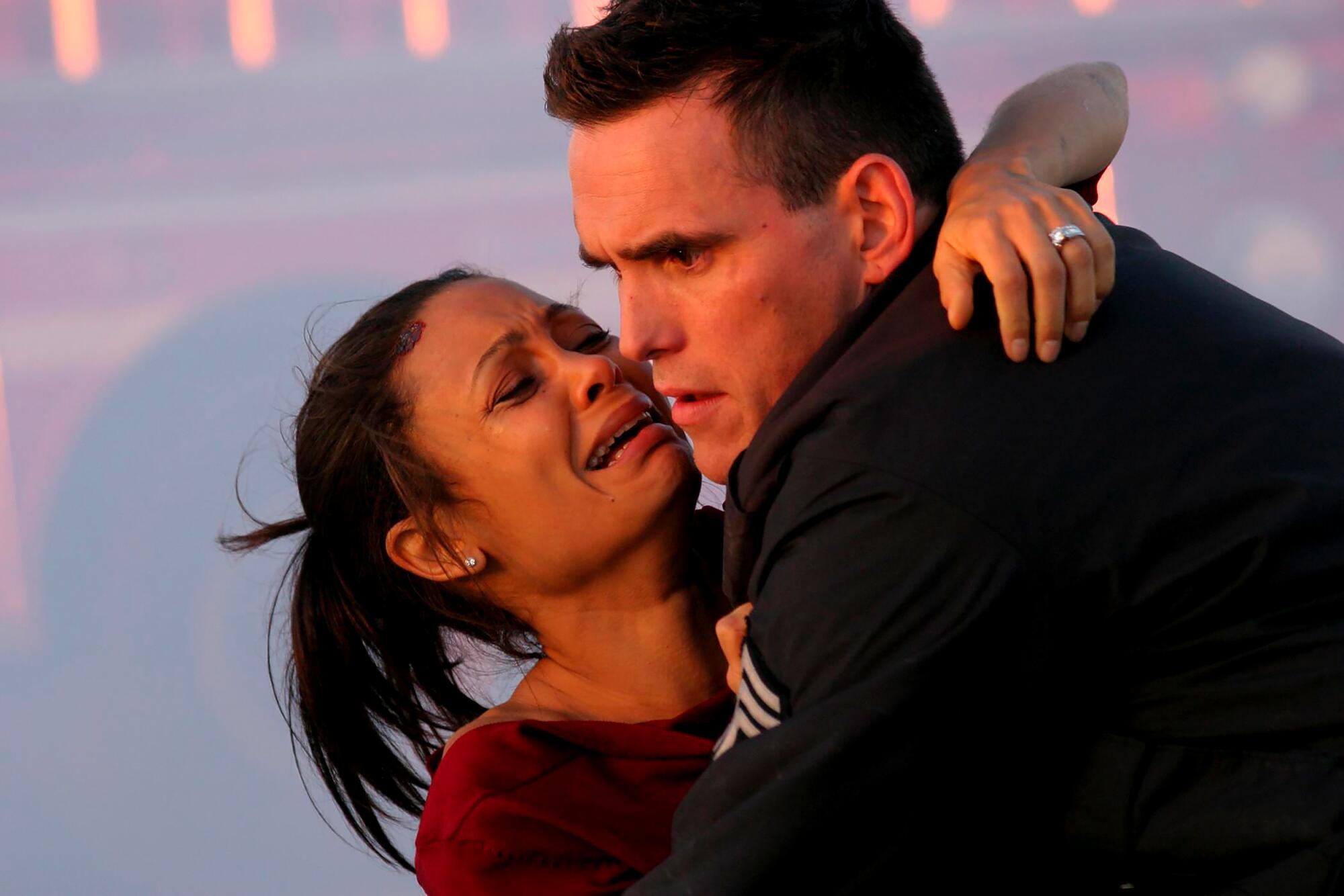 A crying woman holds onto a police officer.