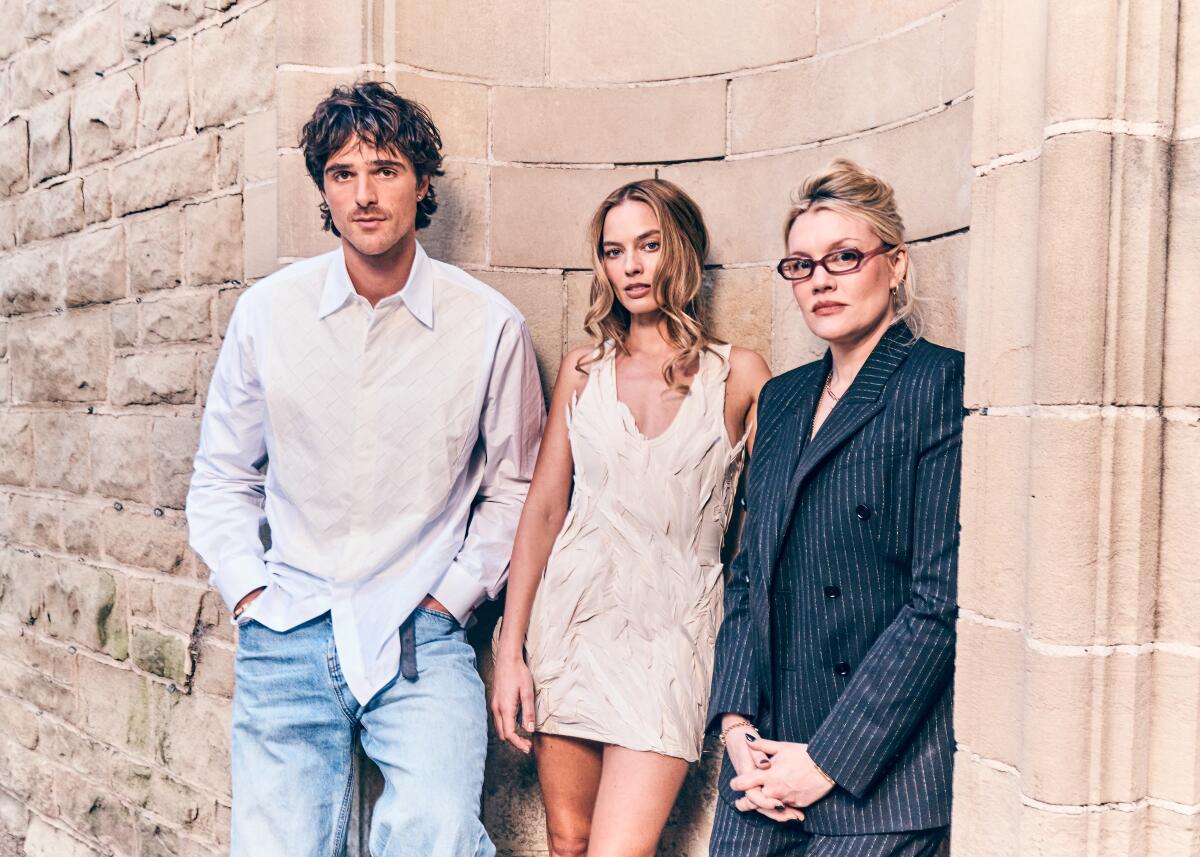 Three film collaborators pose in front of a stone wall.