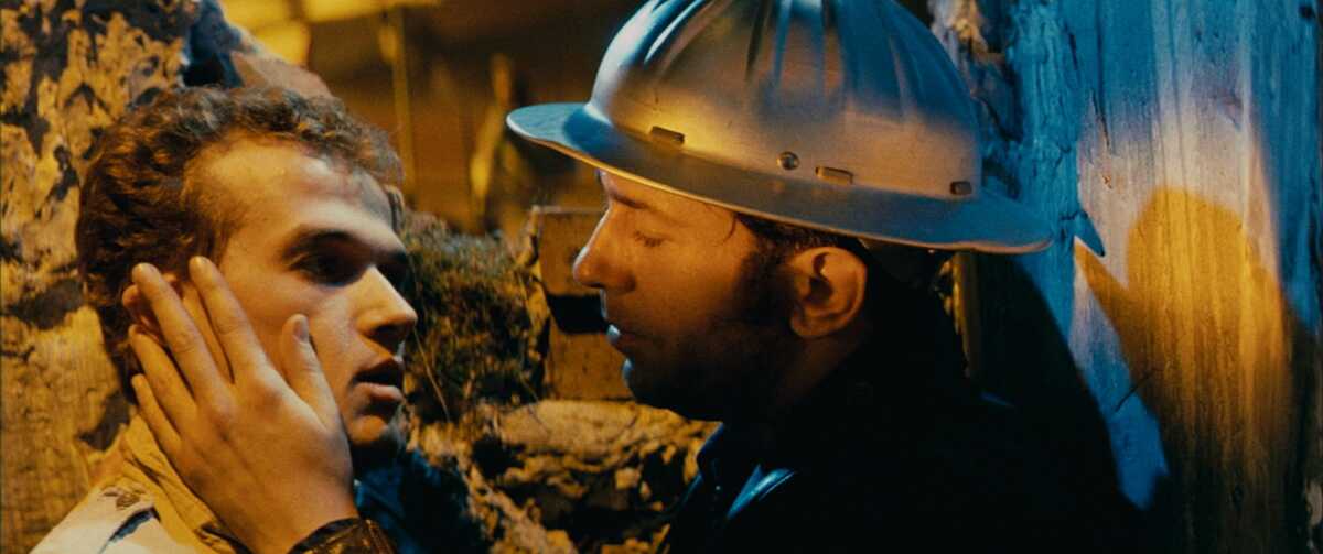 Two men kiss tenderly.