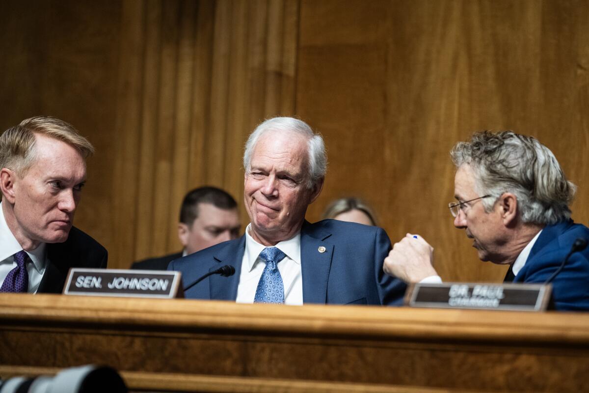 three men talk during the Senate Homeland Security and Governmental Affairs Committee hearing