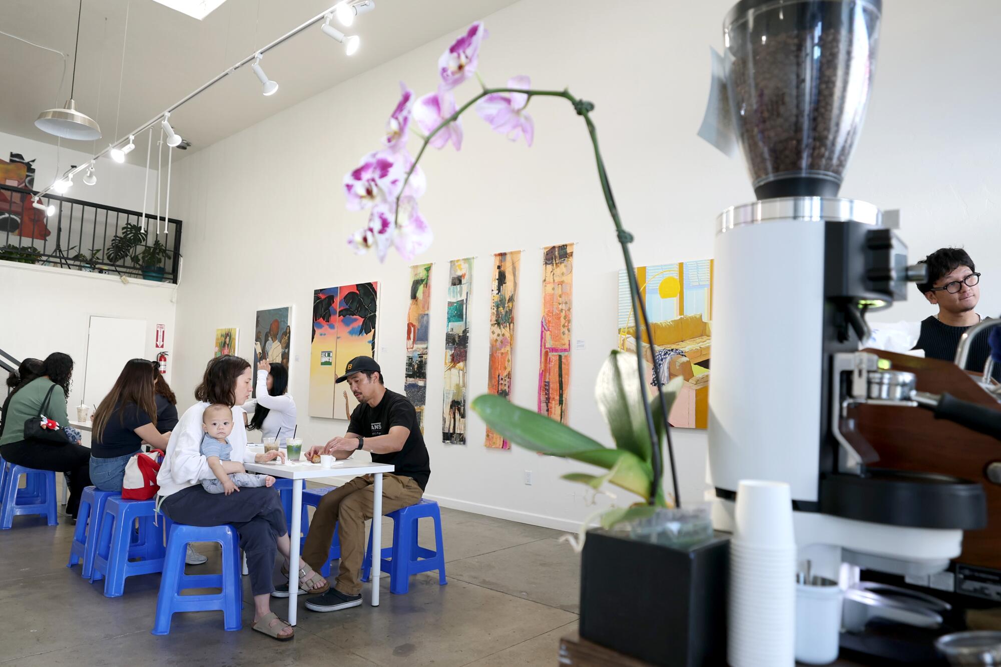 Customers sit at tables inside Open Gallery with the coffee drinks from Reinne's Place. 