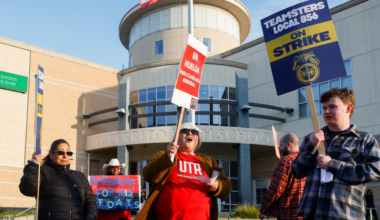 People hold strike signs in front of El Cerrito High School, protesting for better wages and support for students.