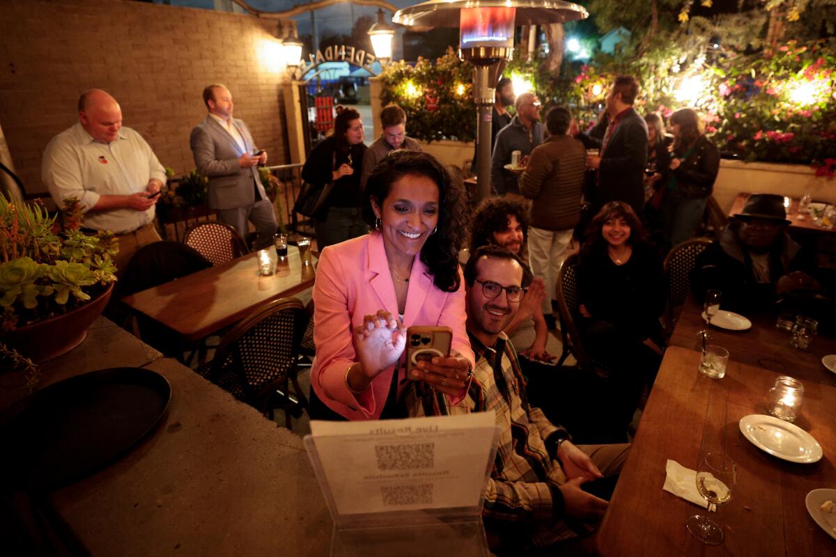 Los Angeles City Councilmember Nithya Raman scans a QR code to get election updates at an election party.