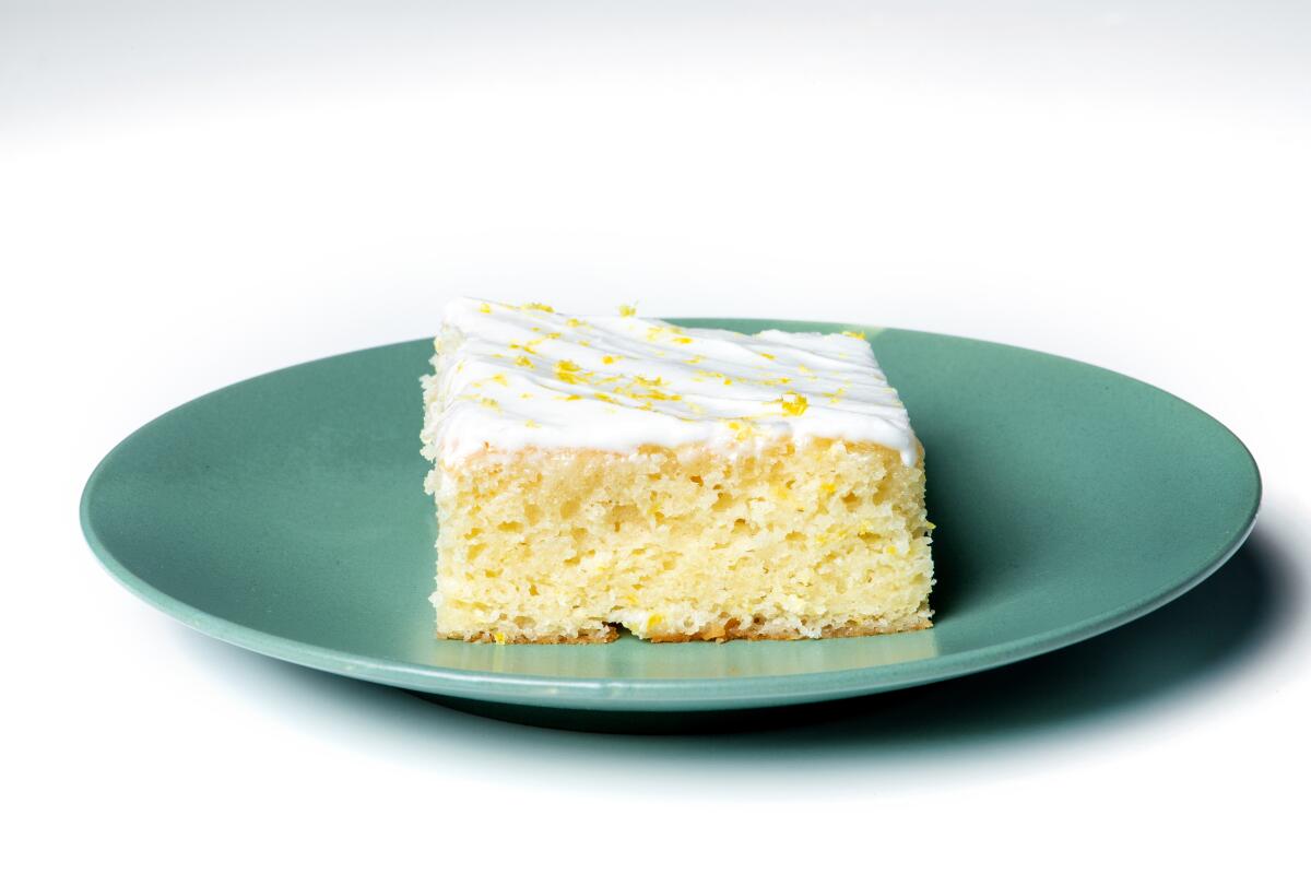 A slice of Lemon Buttermilk Sheet Cake on a green plate. 