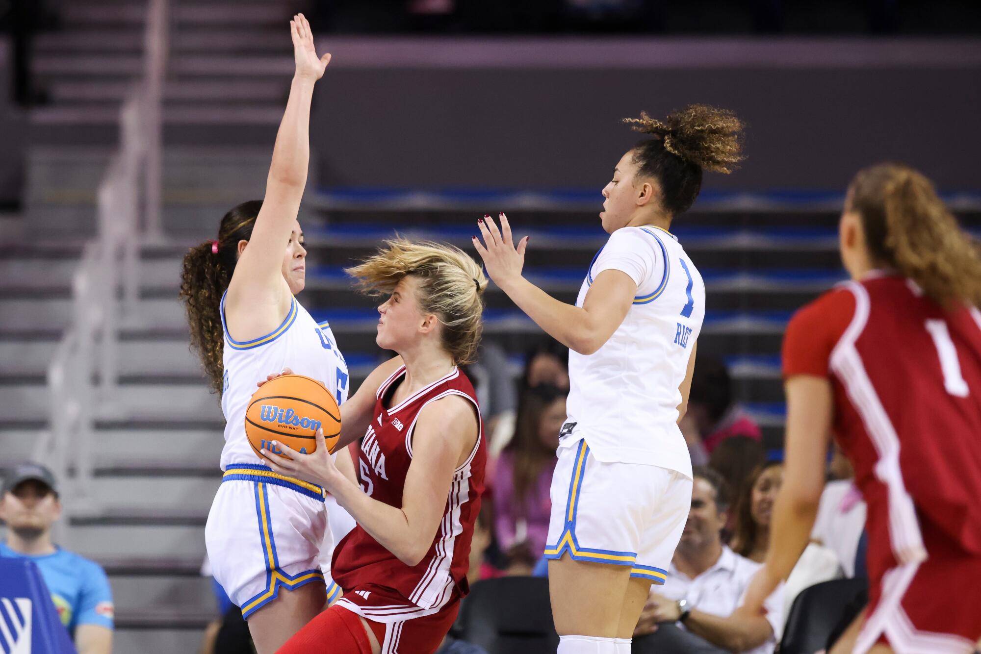 Indiana guard Lenée Beaumont tries to the basket under pressure from UCLA guards Charlisse Leger-Walker and Kiki Rice.