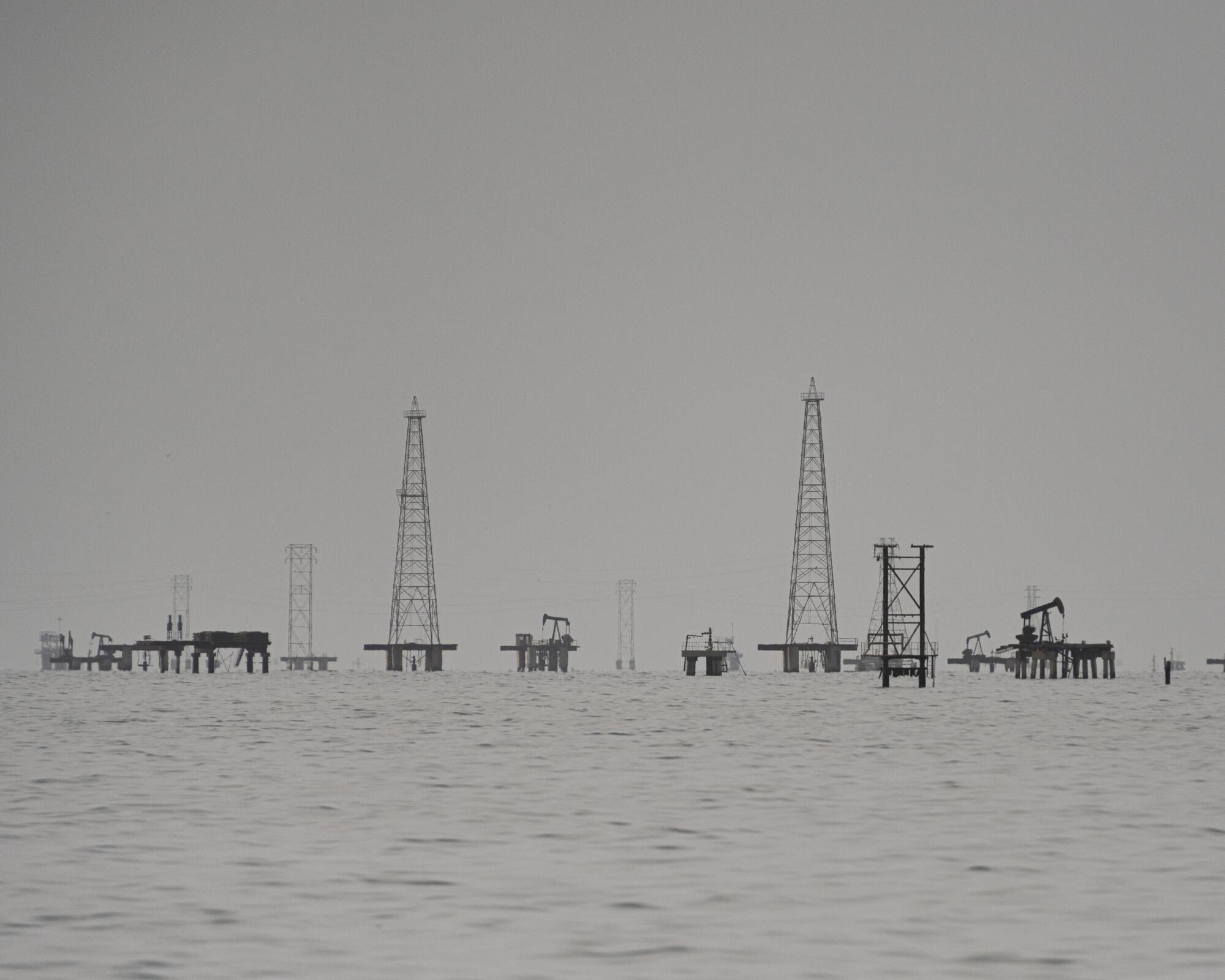 deteriorated oil rigs with towers, oil pumpjacks and gas flow stations