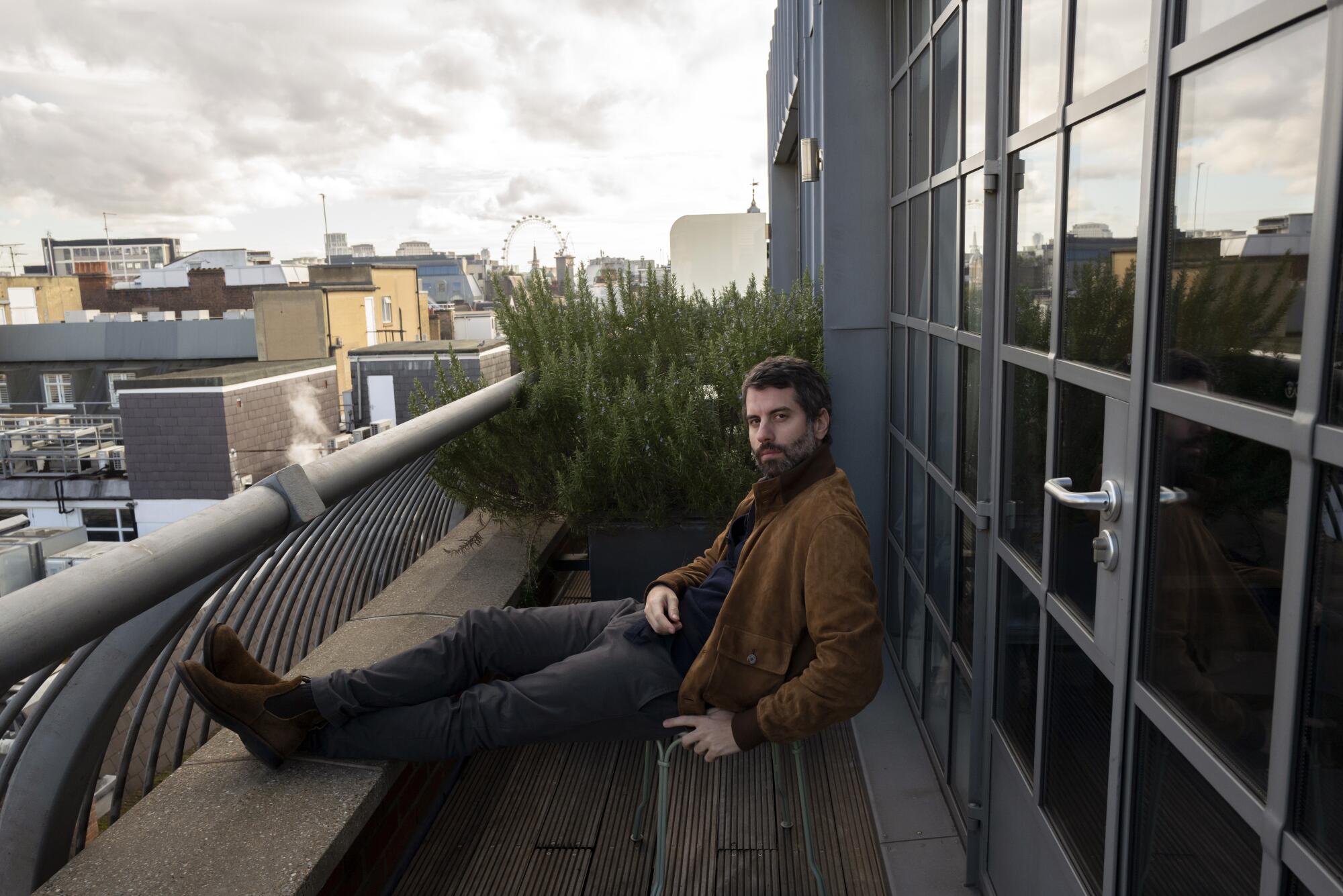 Adolpho Veloso sits outside on a balcony in London.
