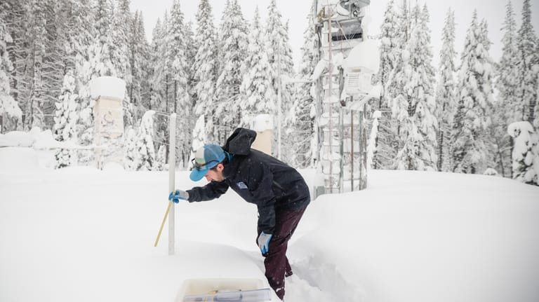 Dr. Gabe Lewis, a research scientist, measures snow depth and...