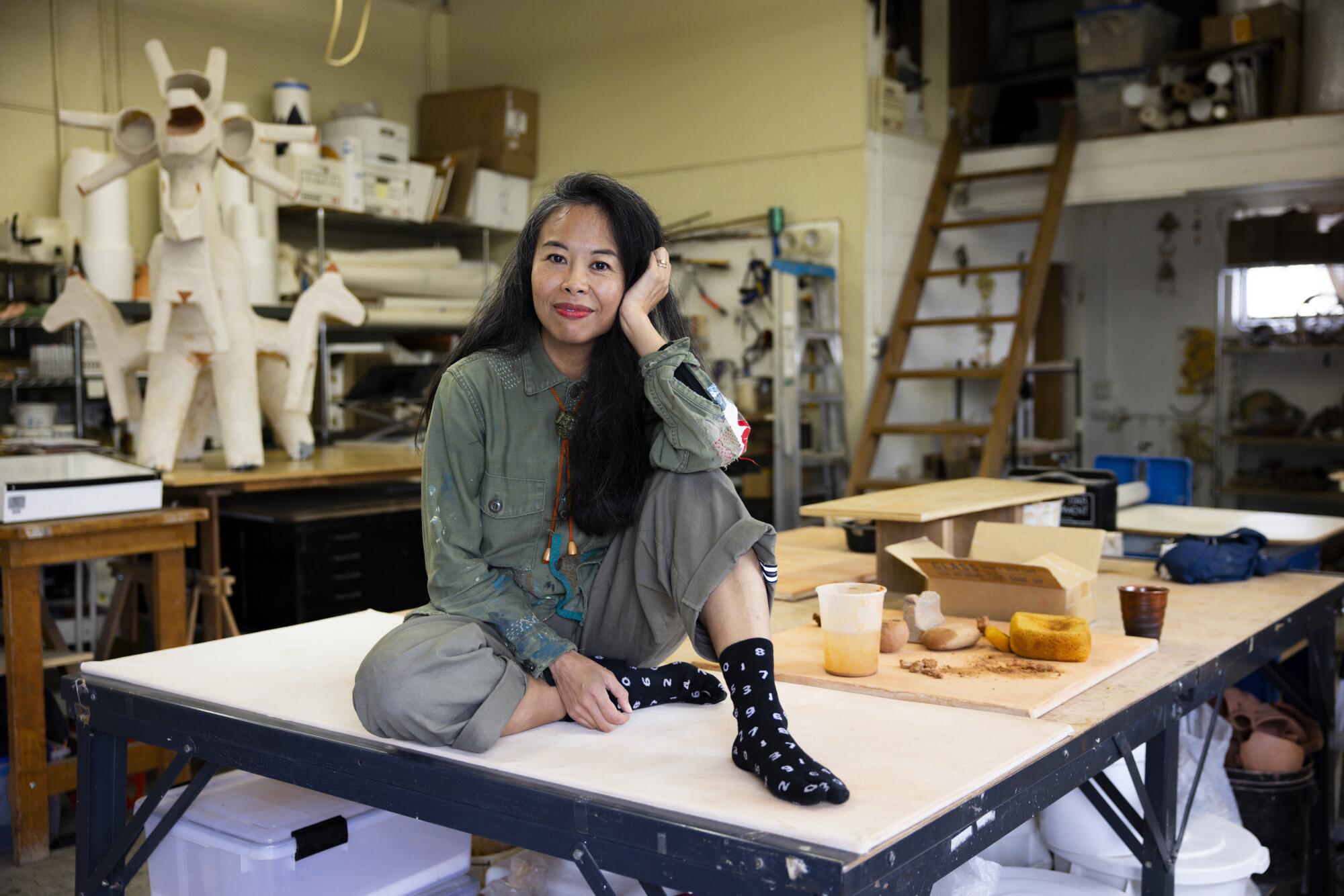 Ako Castuera sits on a table in her studio.