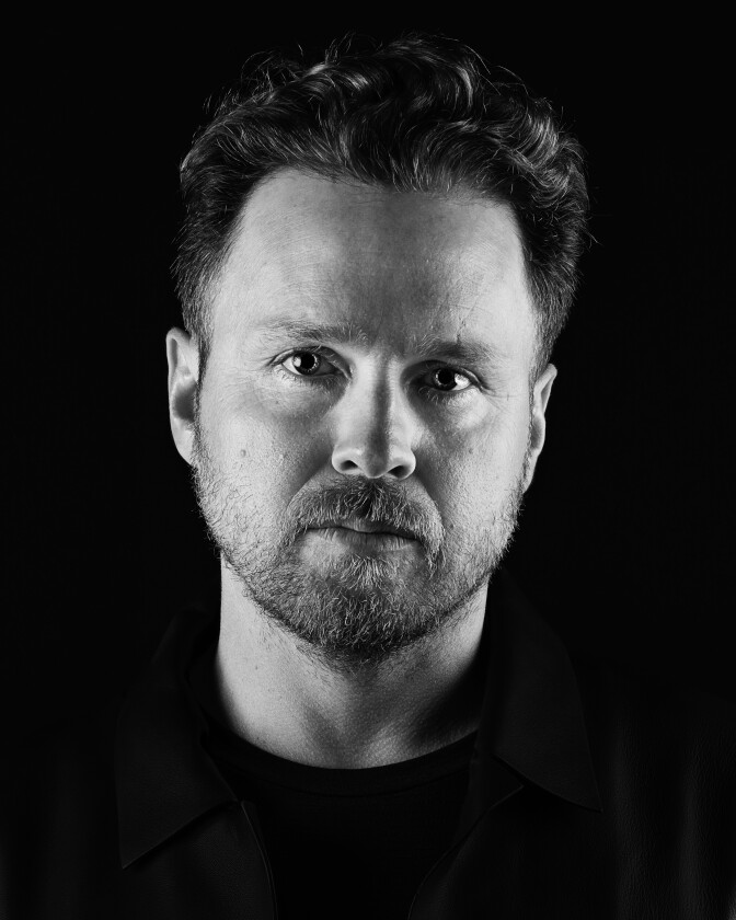 A man with a mustache and beard stares directly into the camera.