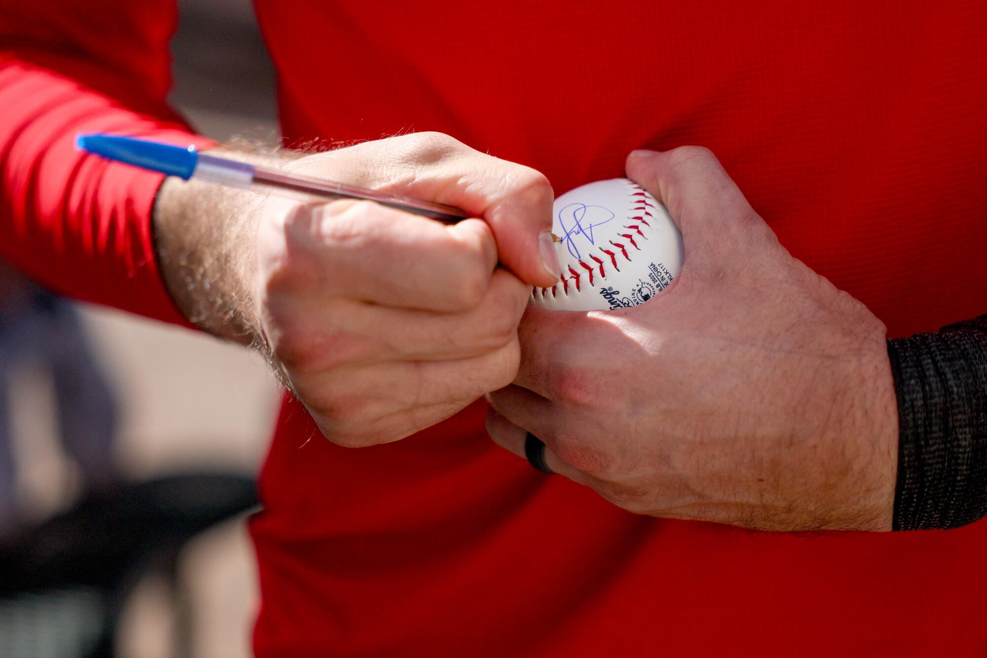 Josh Lowe signs a baseball.