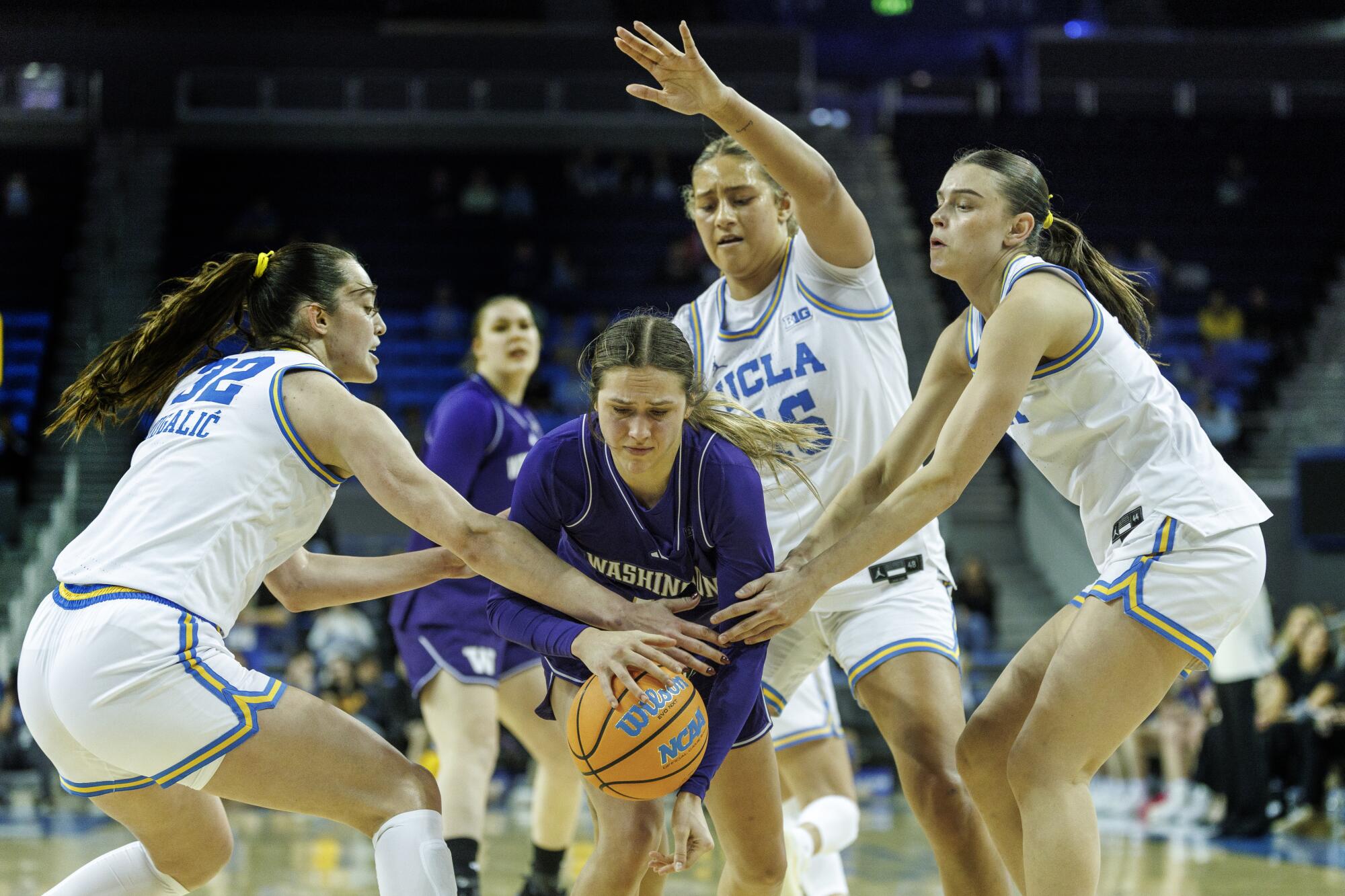UCLA's Angela Dugalic, Sienna Betts and Gabriela Jaquez swarm Washington guard Hannah Stines at Pauley Pavilion.