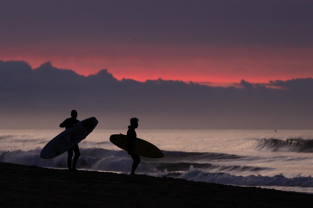 A dramatic pre-dawn stormy sky silhouettes surfers as they look for a good break