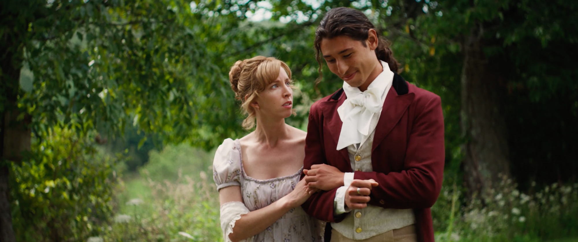 Two people walk arm in arm outside.