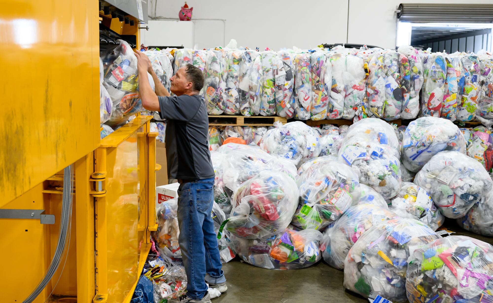 a Ridwell employee inserts a bag of recyclables into a compressing machine