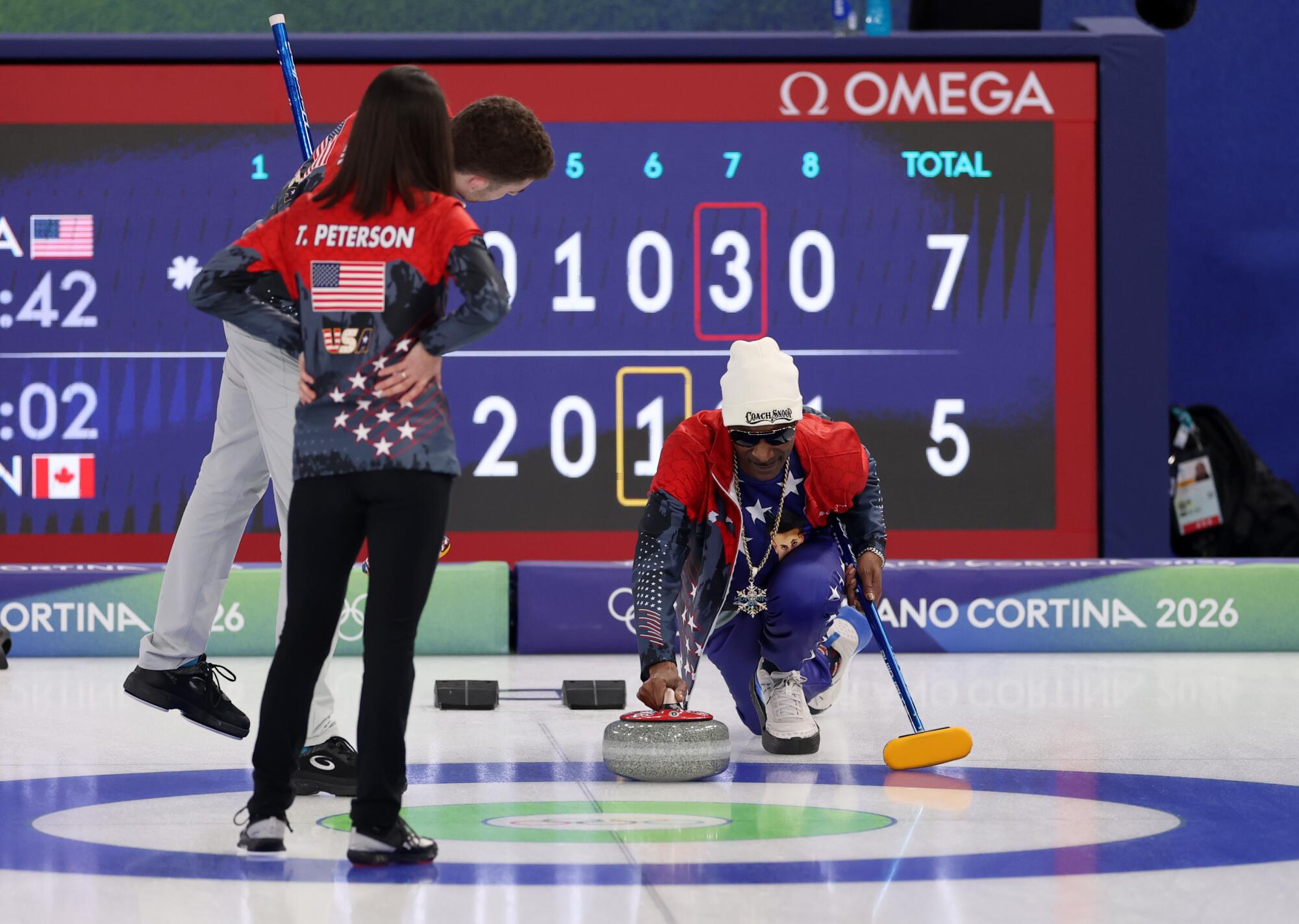 Honorary Team USA coach Snoop Dogg throws a curling stone as Americans Daniel Casper and Tabitha Peterson Lovick watch.