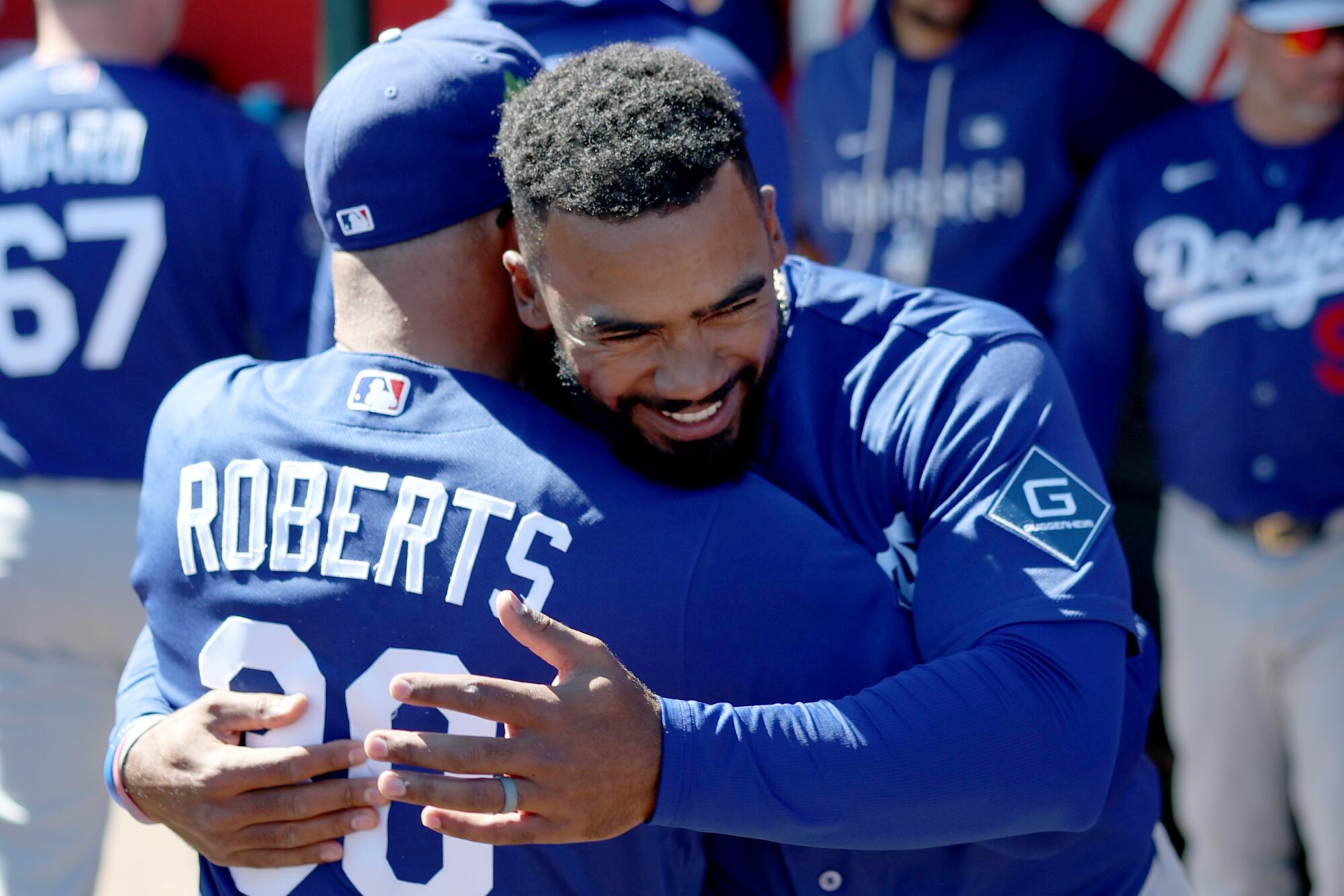 Dodgers right fielder Teoscar Hernandez hugs Dodgers manager Dave Roberts after scoring in the first inning.