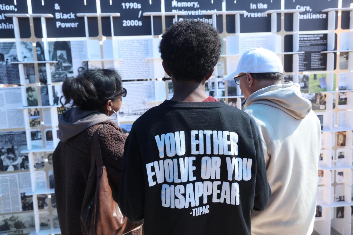 three people looking at an exhibit wall