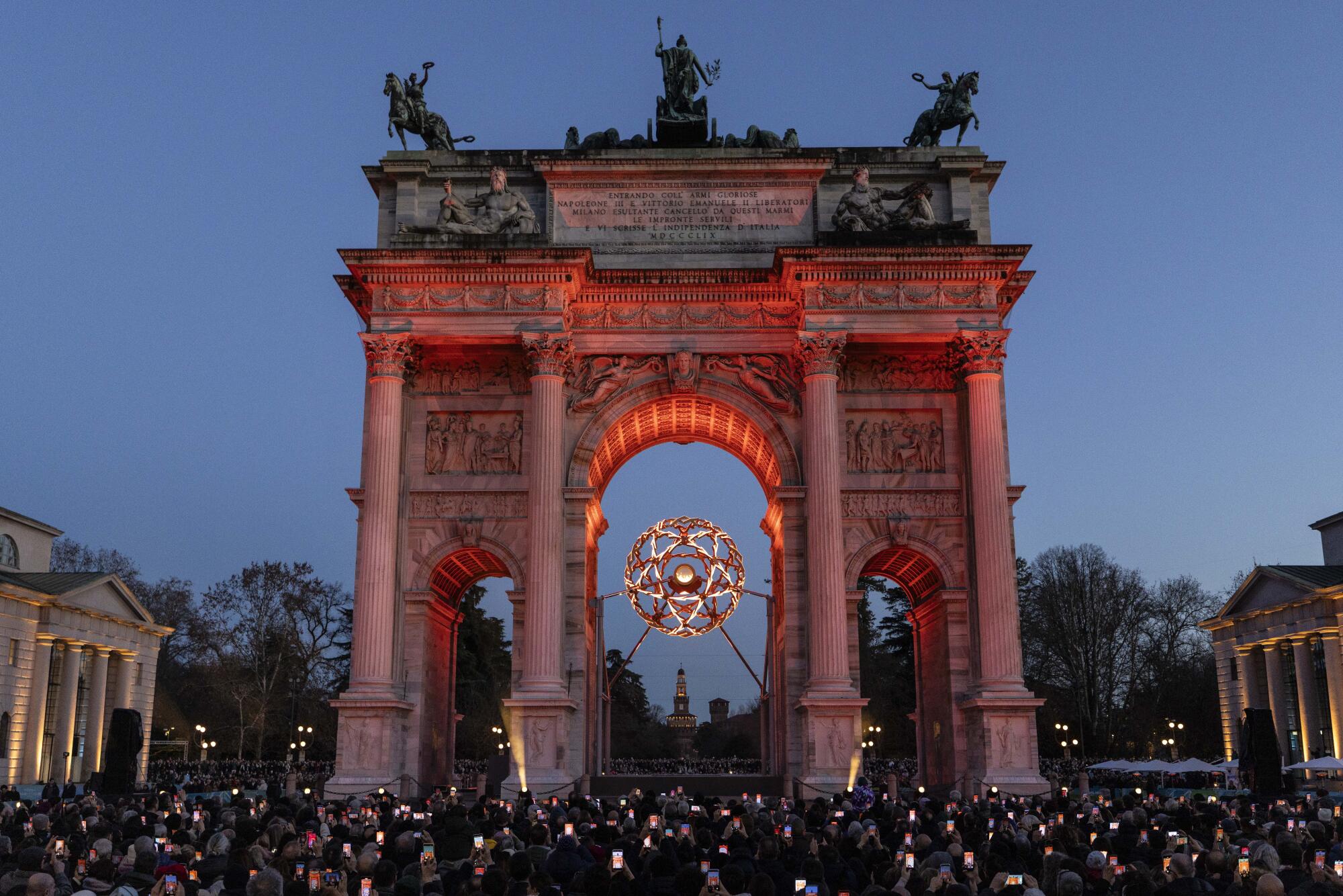 Visitors take pictures of the Olympic cauldron at the Arco della Pace in Milan on Feb. 15.
