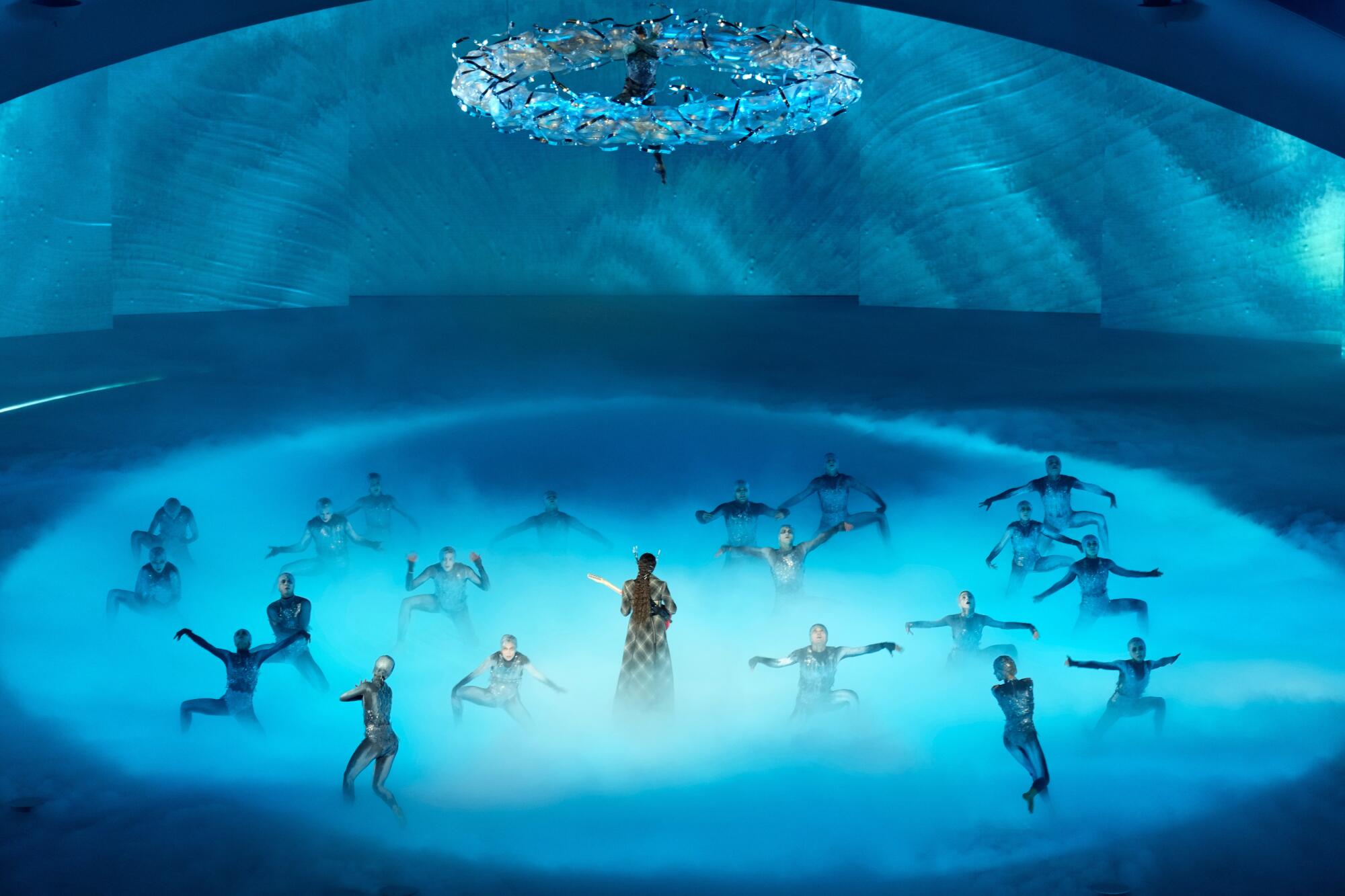 Artists perform on a stage with blue lighting